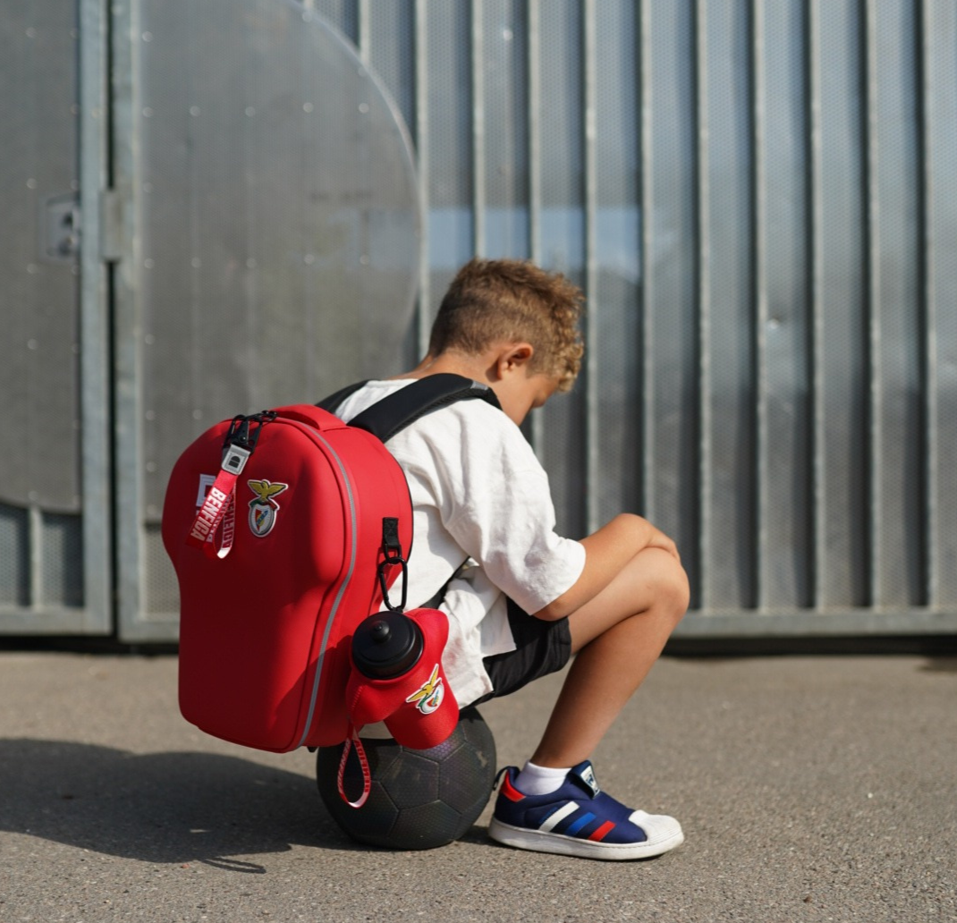 Boy with a Benfica backpack size medium while sitting on a football