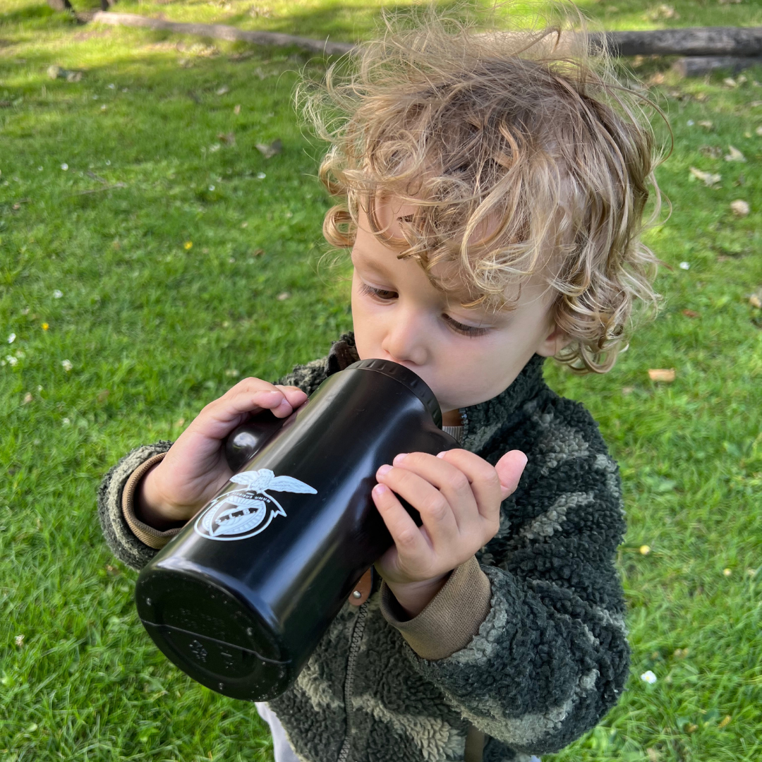 Kid drinking from a Benfica bottle 